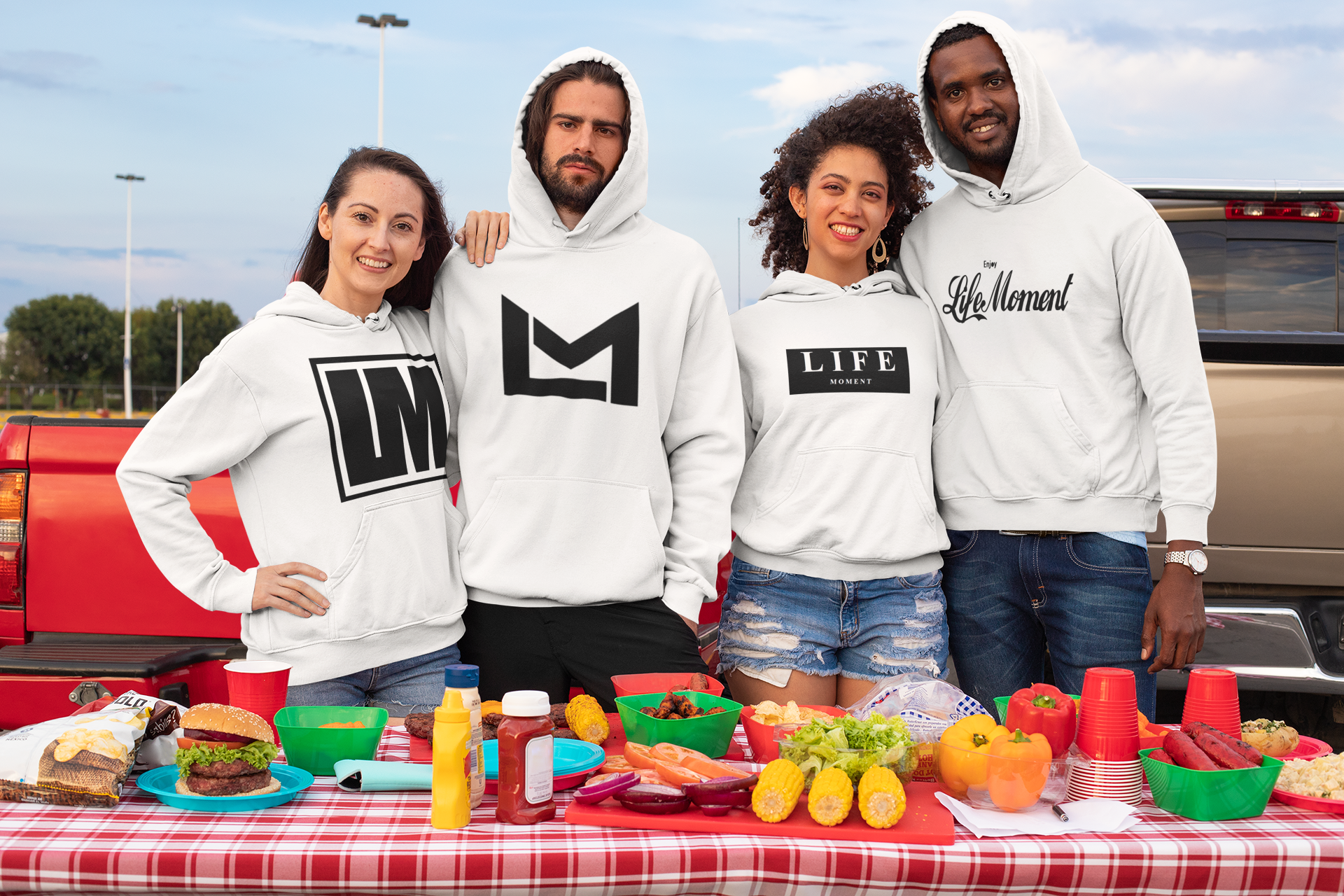 A group of friends wearing Life Moment Apparel hoodies at a tailgate party in a mockup.