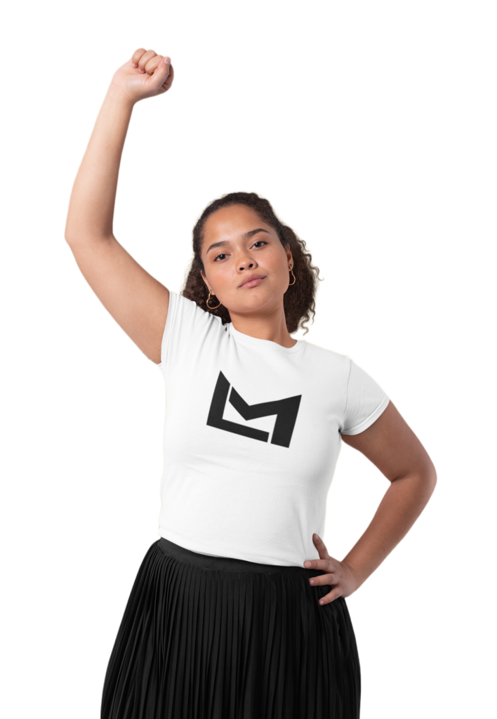 A close-up of a young girl wearing an LM T-shirt, standing confidently with her arm raised and fist clenched in a show of strength and determination. She has a determined expression on her face and her long brown hair flows behind her. The background is blurred, drawing attention to the girl and her message.