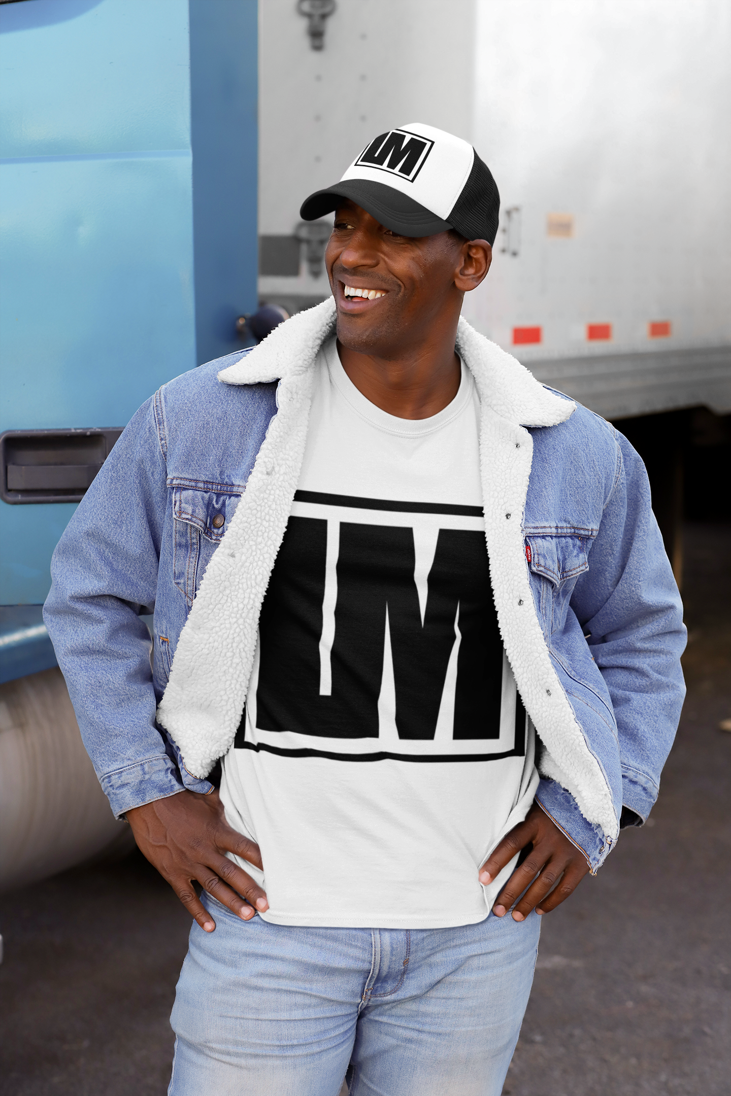 A man wearing a white Life Moment T-shirt and a black and white Life Moment trucker hat stands on a city street.